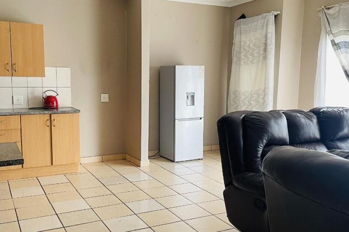 An open-plan living and kitchen area featuring tiled flooring and functional laminate cabinetry, offering a practical layout for daily living.