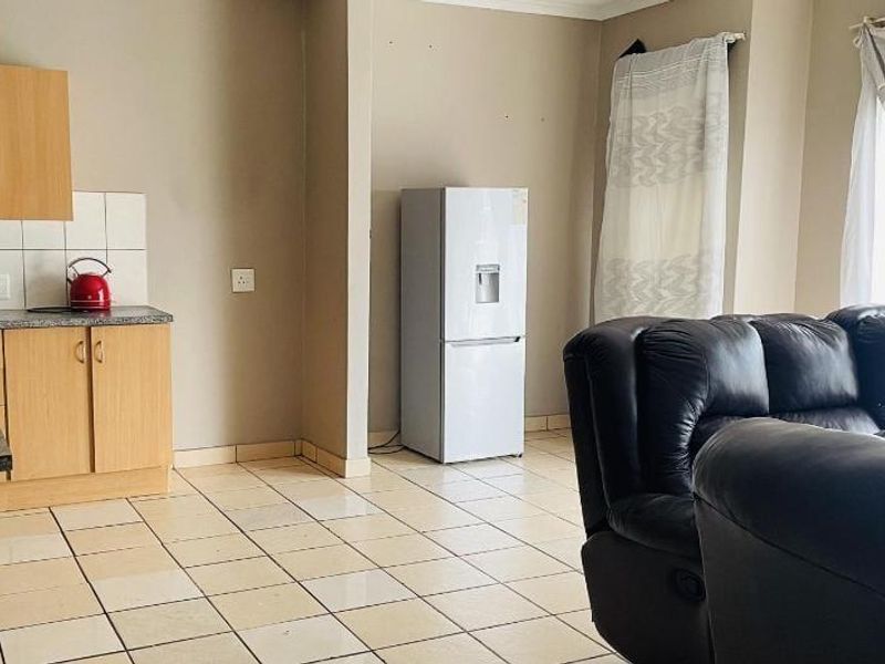 An open-plan living and kitchen area featuring tiled flooring and functional laminate cabinetry, offering a practical layout for daily living.