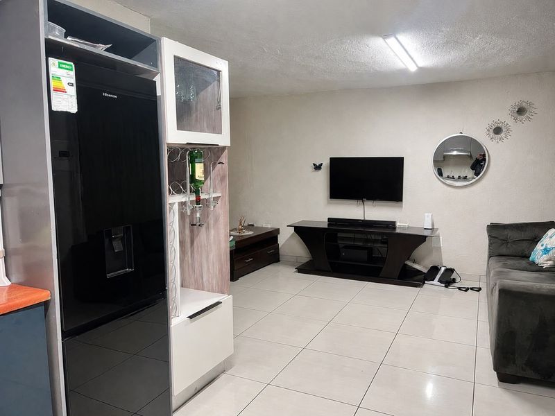 A living room area featuring neutral ceramic floor tiles and a standard ceiling light fixture.