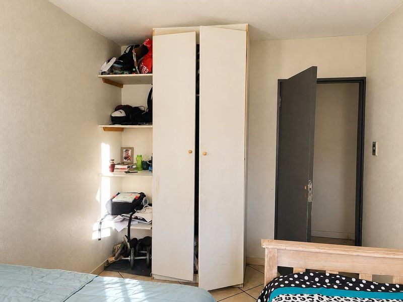 Bedroom featuring a built-in wardrobe with integrated open shelving and tiled flooring.