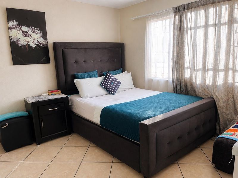 A bedroom featuring neutral wall paint and ceramic floor tiles, providing a functional space with natural light from the window.