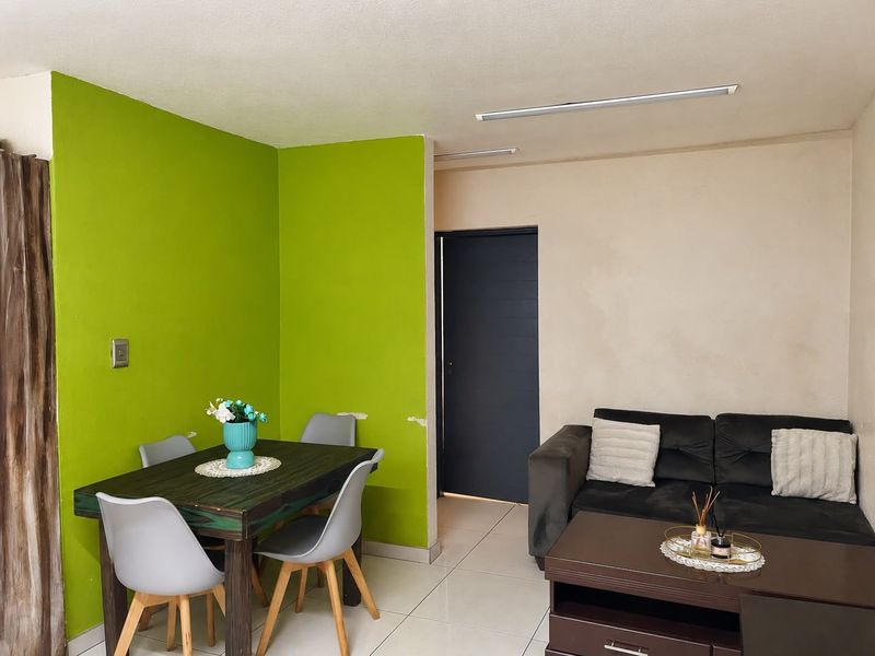 Open plan living and dining area featuring tiled flooring and a vibrant accent wall, providing a functional space for daily living.