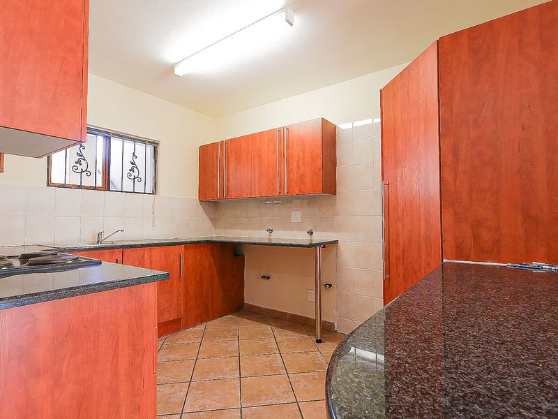 A functional kitchen featuring laminate cabinetry, granite countertops, ceramic tile backsplash, and tiled flooring, offering a clean and practical workspace.