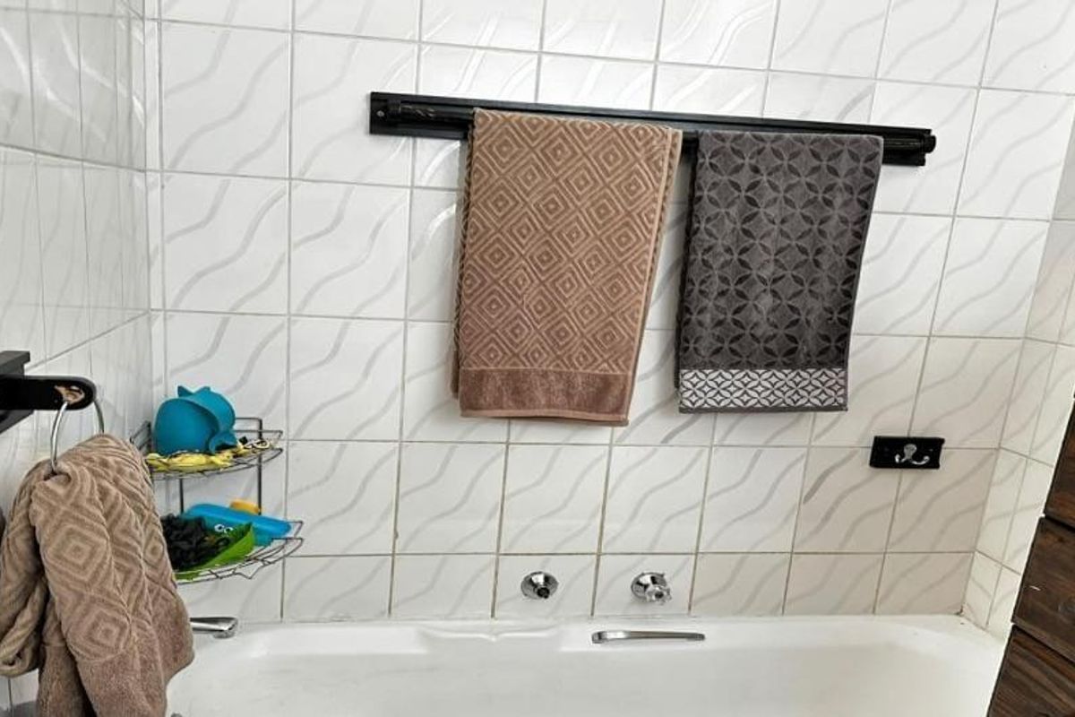 A functional bathroom featuring a bathtub with wall-mounted faucets and tiled wall finishes.