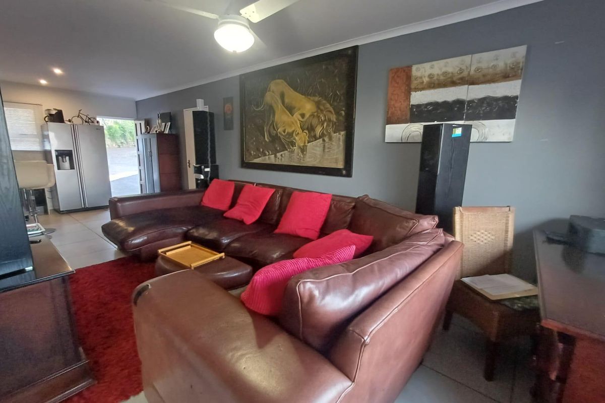 A spacious living area featuring tiled flooring, a ceiling fan, and recessed lighting, providing a comfortable and functional space for relaxation.