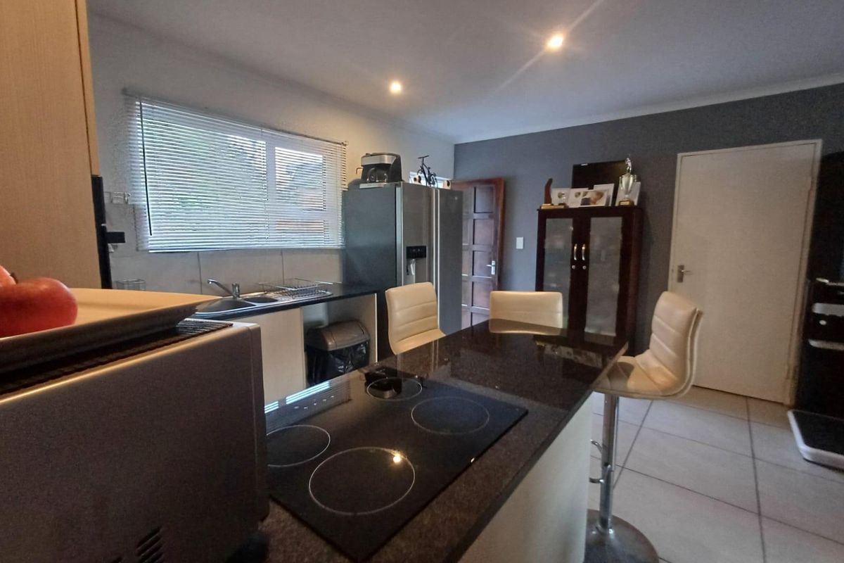 A functional kitchen featuring granite countertops, an integrated electric hob, tiled flooring, and recessed lighting, offering a practical layout for daily meal preparation.