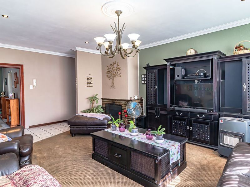 A spacious living room featuring a central fireplace, decorative ceiling rose, and coved ceilings, providing a comfortable and functional family living area.