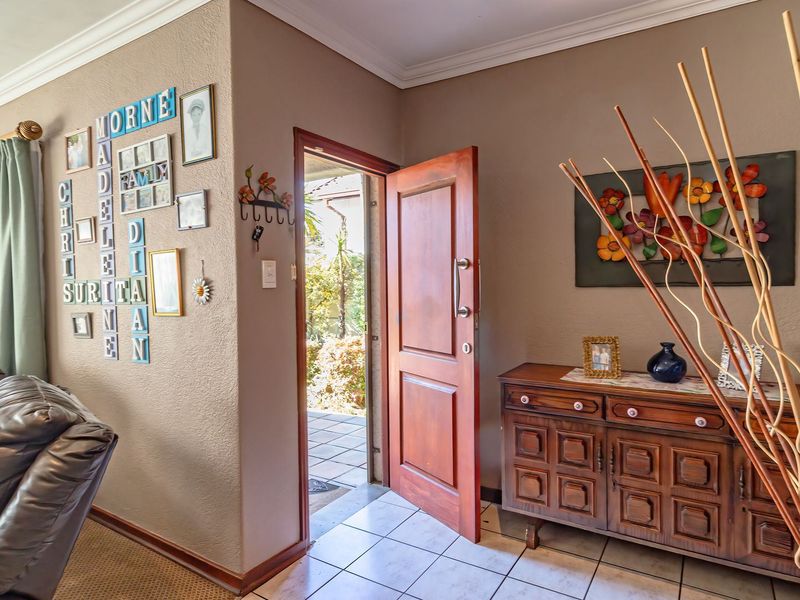 Entrance area featuring tiled flooring, coved ceiling cornicing, and a solid timber front door leading to an outdoor patio space.