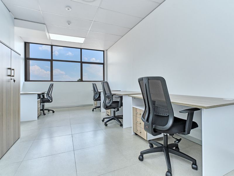 A bright, modern commercial office space featuring tiled flooring, a suspended ceiling, and large windows providing ample natural light.