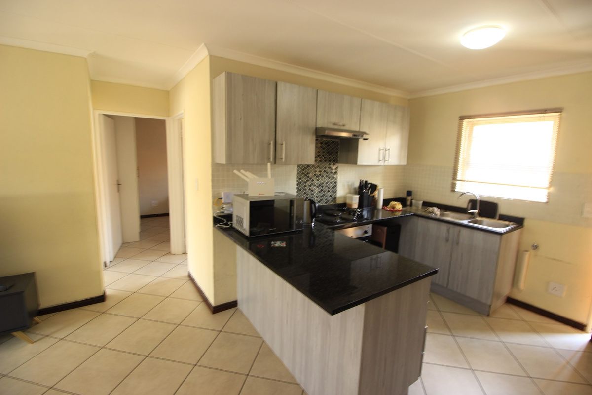 Functional kitchen featuring granite countertops, light wood-finish cabinetry, mosaic backsplash, and tiled flooring, offering a practical layout for daily meal preparation.