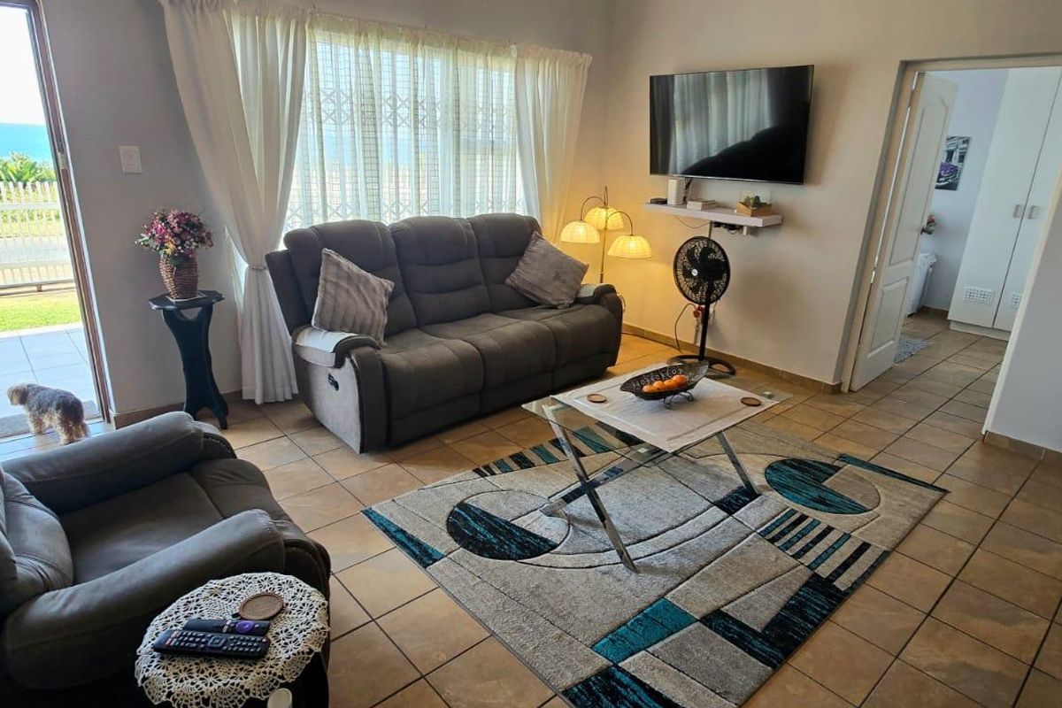 A comfortable living room featuring tiled flooring and a sliding glass door that provides access to an outdoor area with a view.
