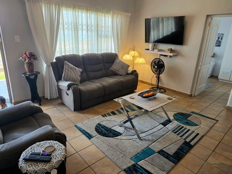 A comfortable living room featuring tiled flooring and a sliding glass door that provides access to an outdoor area with a view.