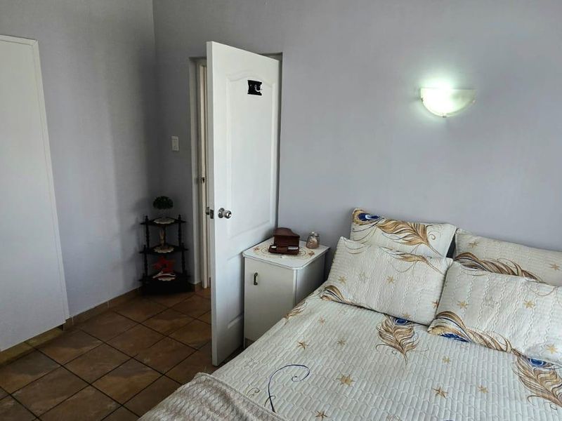 A functional bedroom featuring tiled flooring, a built-in wardrobe, and a wall-mounted light fixture.