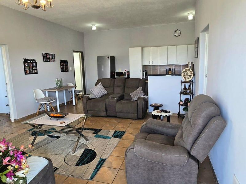 Open plan living area featuring tiled flooring and a compact kitchen with built-in cabinetry and a breakfast bar.