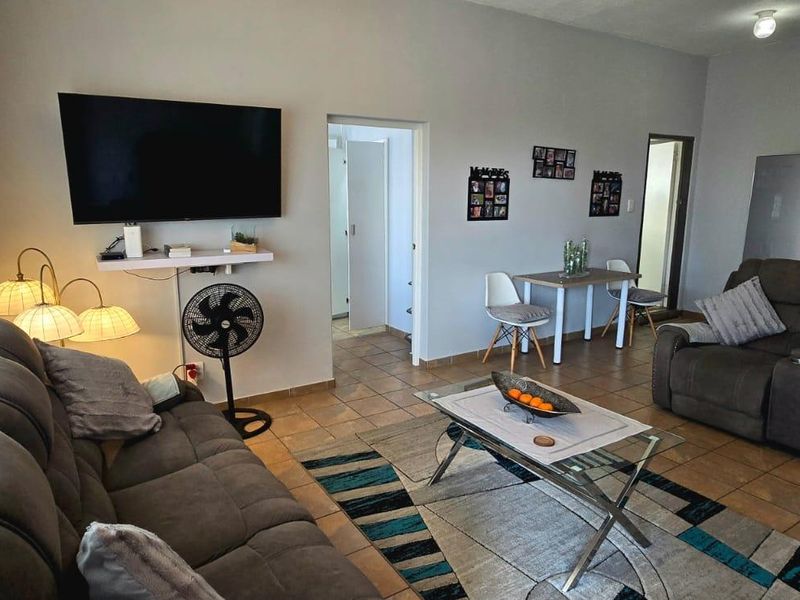 An open-plan living area featuring tiled flooring and direct access to an outdoor space through a sliding door.