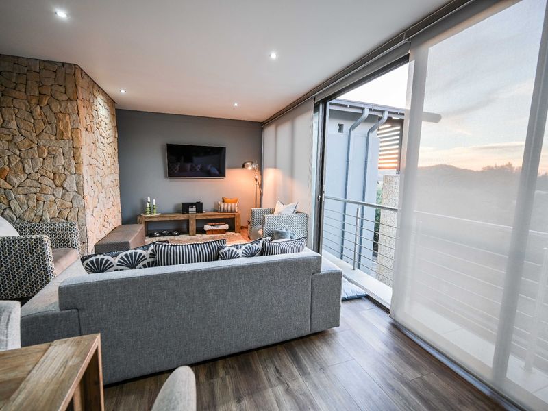 Modern living room featuring a stone accent wall, laminate flooring, and large sliding glass doors opening onto a balcony with scenic views.