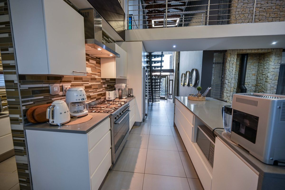 Modern kitchen featuring stone countertops, gas hob, and built-in cabinetry, with an open-plan layout leading to a mezzanine level and spiral staircase.