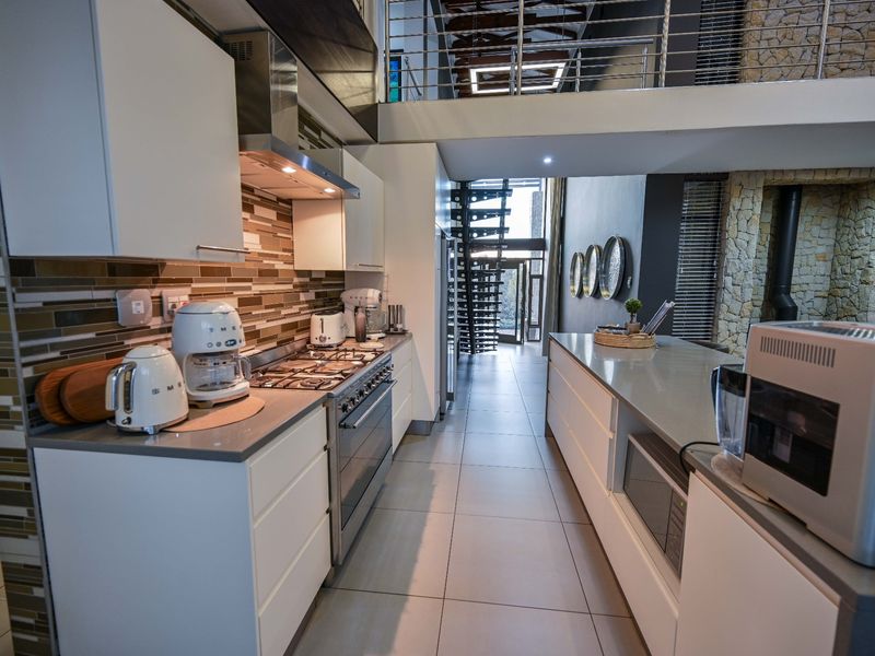 Modern kitchen featuring stone countertops, gas hob, and built-in cabinetry, with an open-plan layout leading to a mezzanine level and spiral staircase.