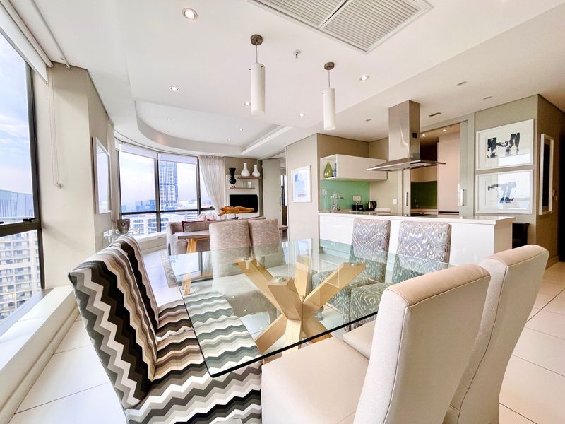 Modern open-plan living and dining area featuring floor-to-ceiling windows with city views, recessed lighting, and a sleek kitchen with integrated appliances.