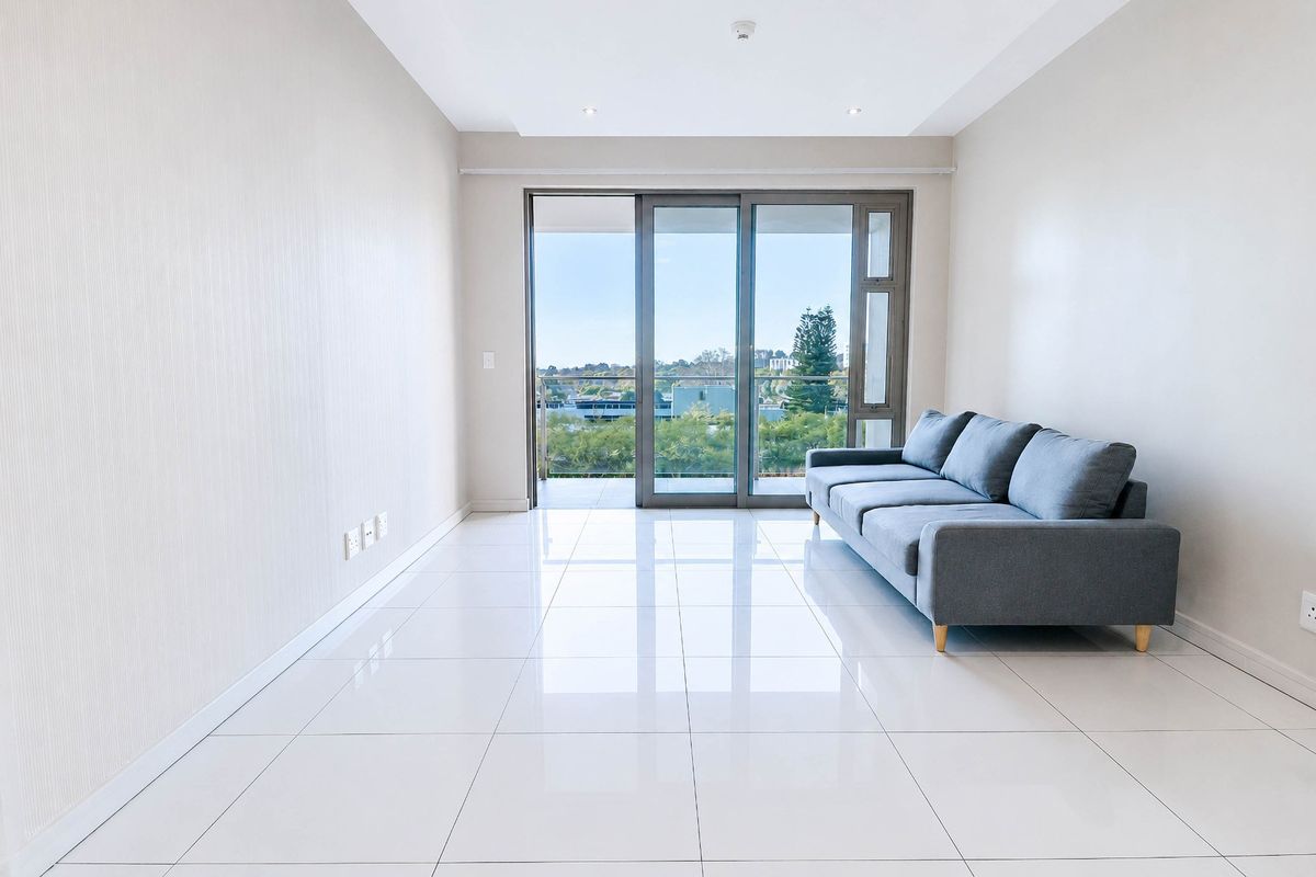 Bright and modern living area featuring polished tiled floors, recessed lighting, and large sliding glass doors leading to a private balcony with scenic views.