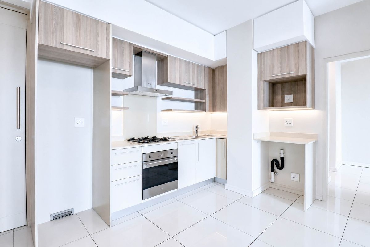 Modern kitchen featuring sleek wood-tone and white cabinetry, stone countertops, integrated gas hob, electric oven, and high-quality tiled flooring.