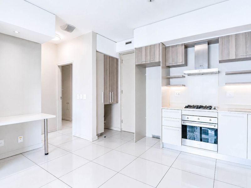Modern kitchen featuring sleek cabinetry, built-in gas hob, oven, extractor fan, and tiled flooring, complemented by a convenient integrated desk area.