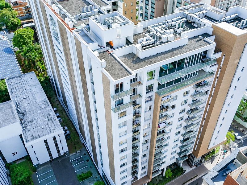 Aerial view of a modern high-rise apartment building featuring multiple balconies, glass railings, and roof-mounted HVAC infrastructure.