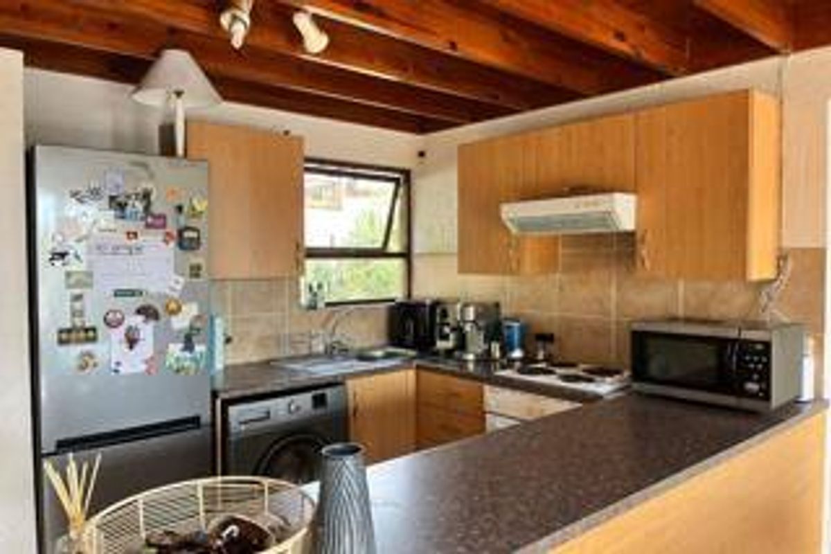 Functional kitchen featuring laminate cabinetry, tiled backsplash, electric hob, extractor fan, and exposed timber ceiling beams.