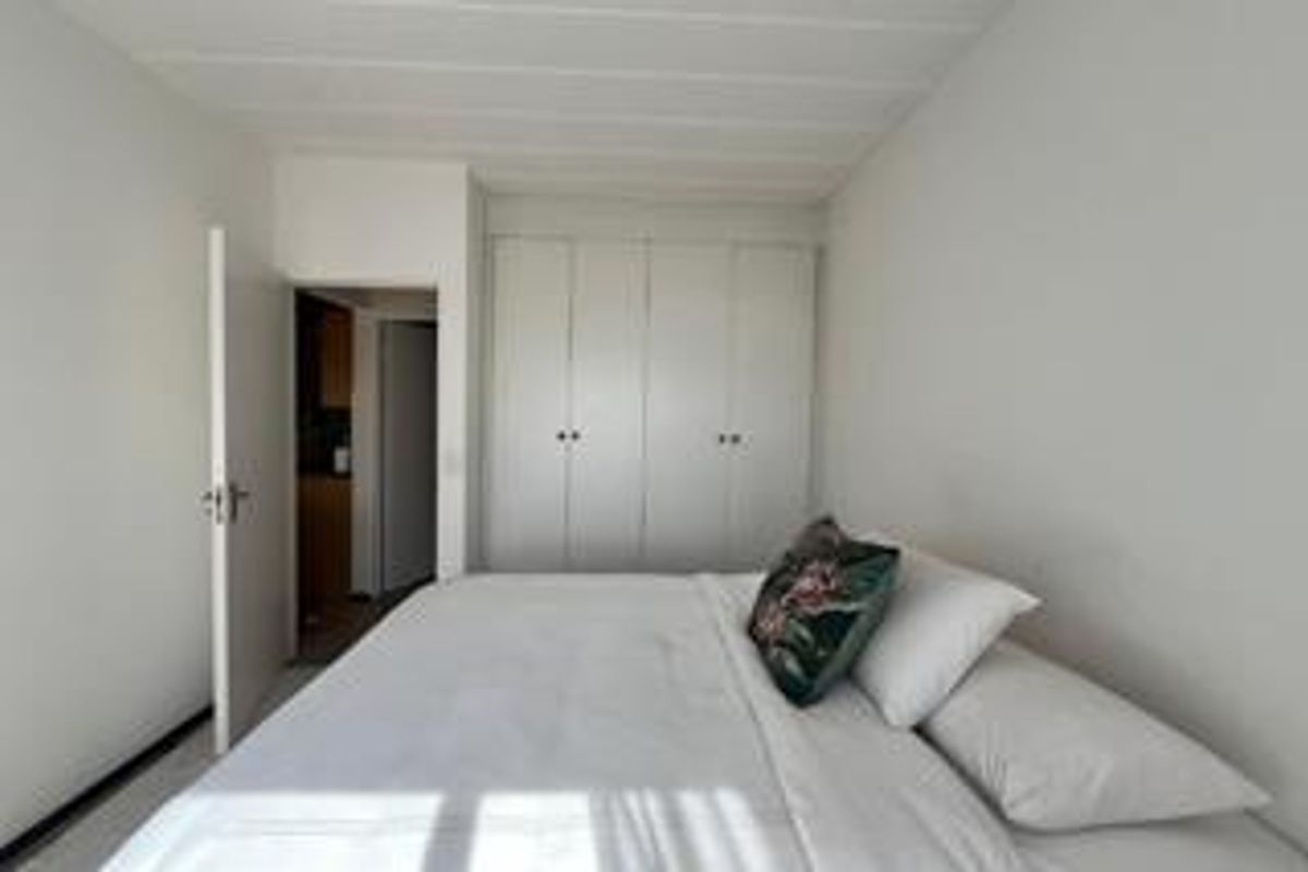 A functional bedroom featuring built-in cupboards and neutral finishes, providing a clean and simple living space.