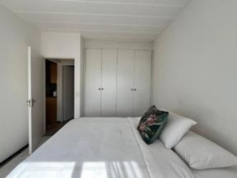 A functional bedroom featuring built-in cupboards and neutral finishes, providing a clean and simple living space.