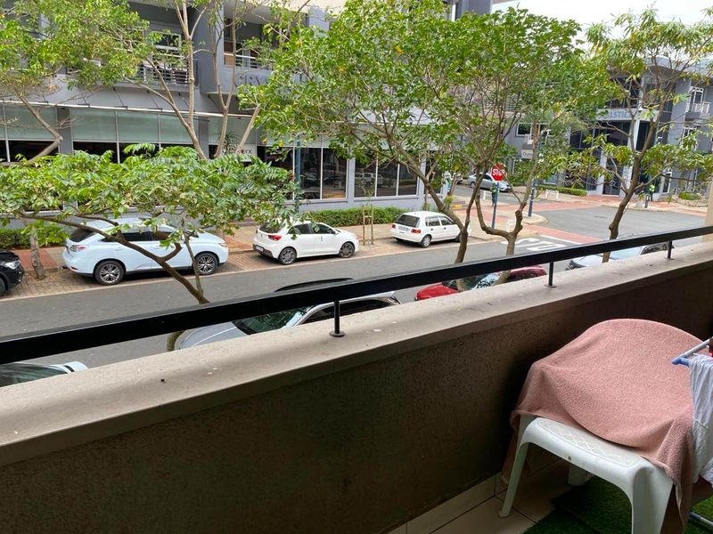 A balcony overlooking a street with a metal balustrade and tiled flooring.