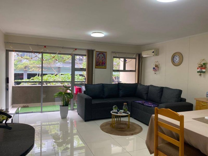 Open-plan living area featuring tiled floors, split-system air conditioning, and large sliding glass doors providing access to a private balcony.