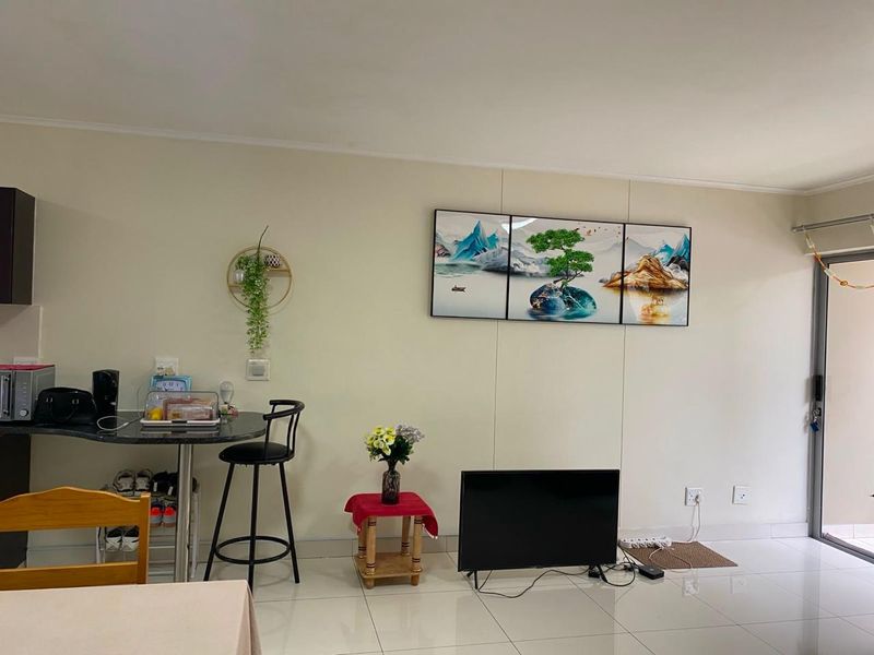 Open plan living area featuring tiled flooring, a breakfast bar, and a sliding door leading to an outdoor space.