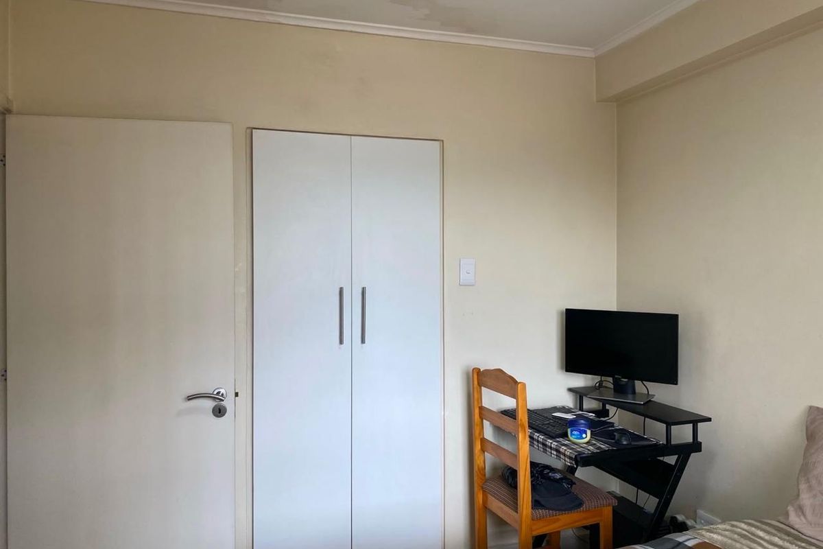 A bedroom featuring a built-in wardrobe and visible water staining on the ceiling, indicating potential maintenance requirements.