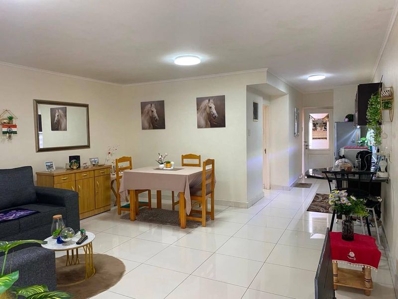 An open-plan living and dining area featuring polished floor tiles, neutral walls, and integrated kitchen cabinetry, creating a bright and functional living space.