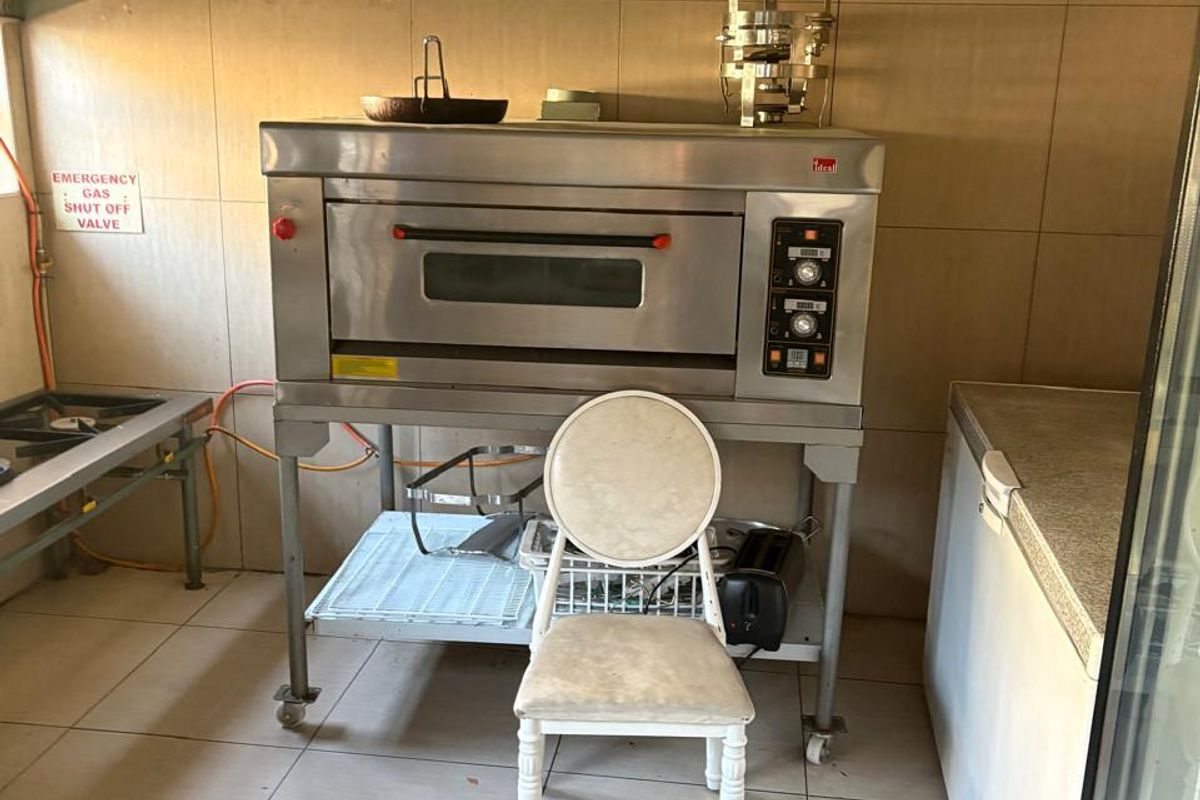 Commercial kitchen area featuring a stainless steel oven, extractor hood, and tiled finishes, suitable for professional food preparation.