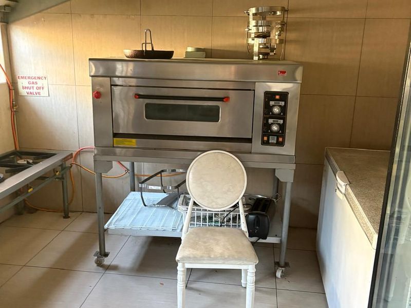 Commercial kitchen area featuring a stainless steel oven, extractor hood, and tiled finishes, suitable for professional food preparation.