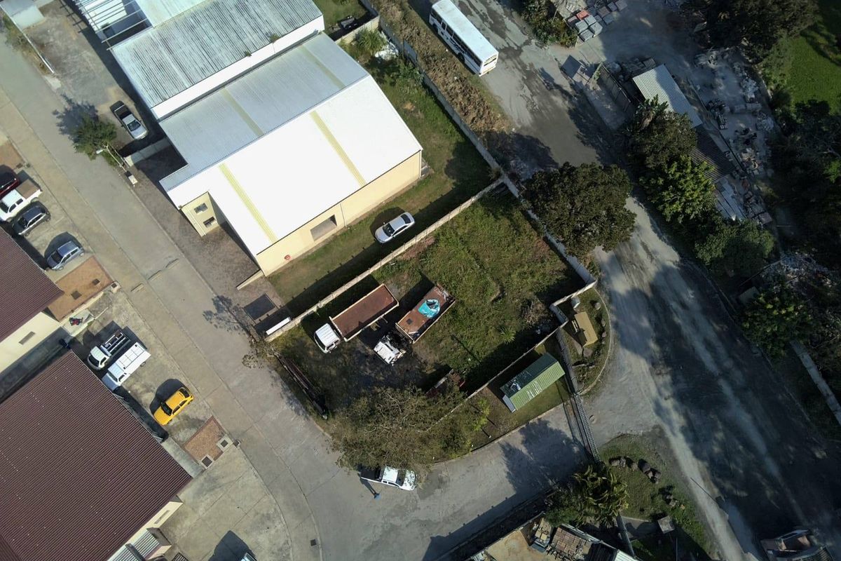 Aerial view of a vacant residential plot featuring perimeter walling and fencing, situated within an established neighborhood setting.