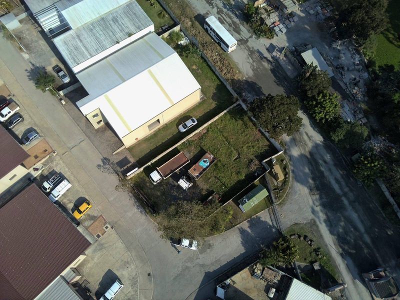 Aerial view of a vacant residential plot featuring perimeter walling and fencing, situated within an established neighborhood setting.