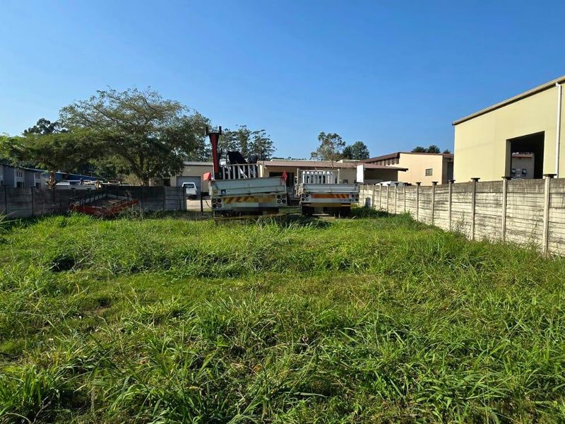 A vacant residential plot featuring a precast concrete boundary wall and established vegetation, suitable for future development.