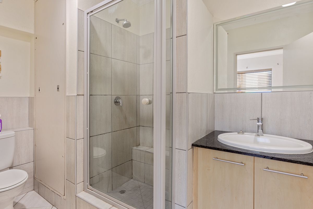A clean, functional bathroom featuring a glass-enclosed shower, vanity with granite countertop, and modern fixtures.