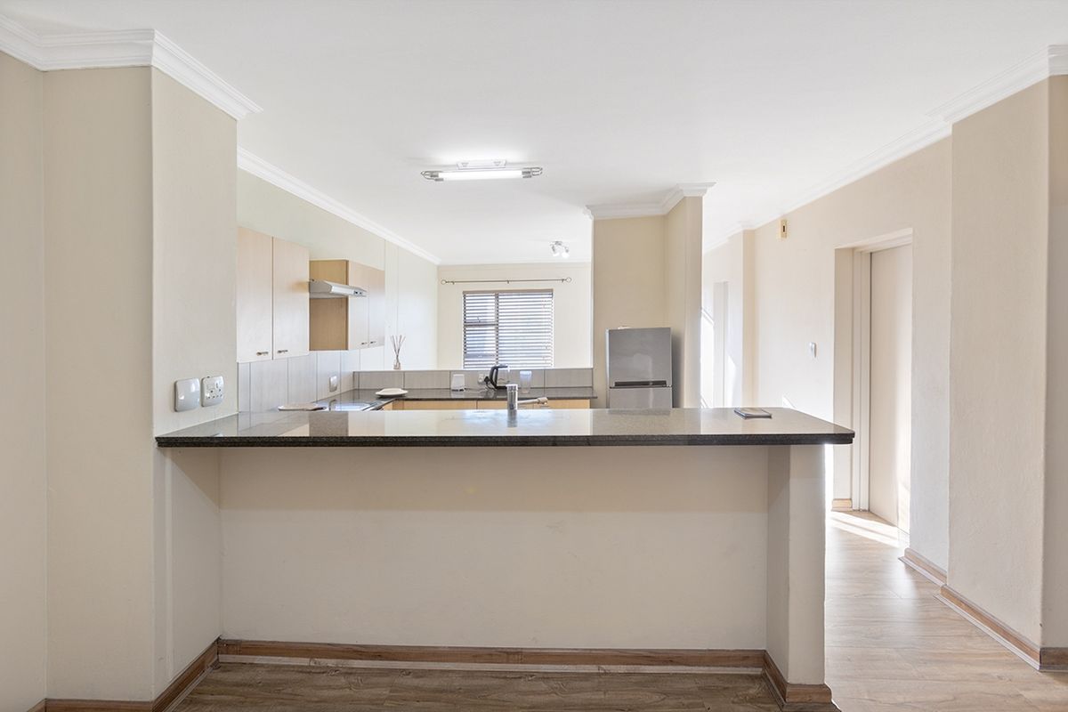 Open plan kitchen and living area featuring a granite breakfast bar, laminate flooring, and neutral cabinetry, offering a functional and versatile living space.