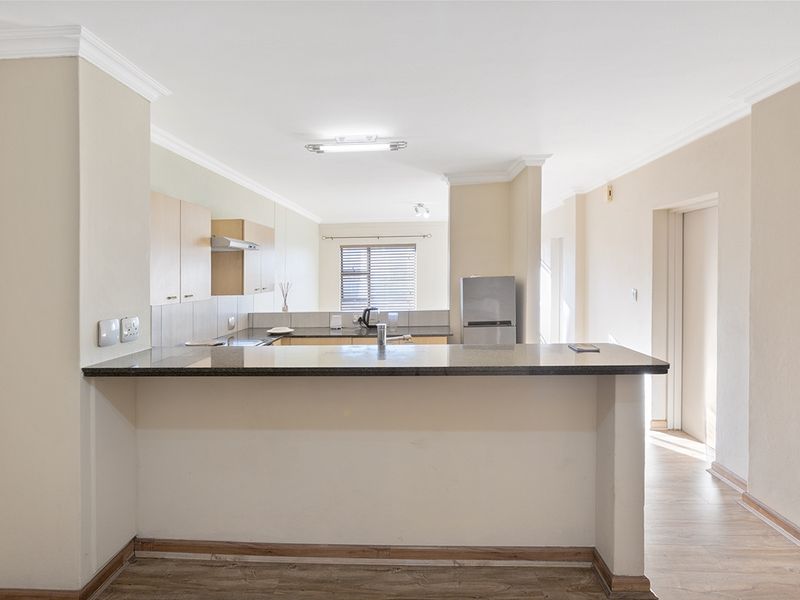 Open plan kitchen and living area featuring a granite breakfast bar, laminate flooring, and neutral cabinetry, offering a functional and versatile living space.