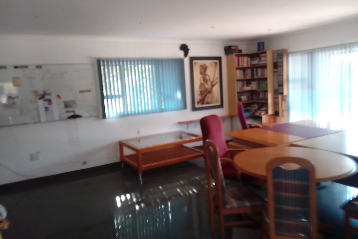 A functional home office space featuring built-in shelving, vertical window blinds, and recessed lighting, providing a practical area for work or study.