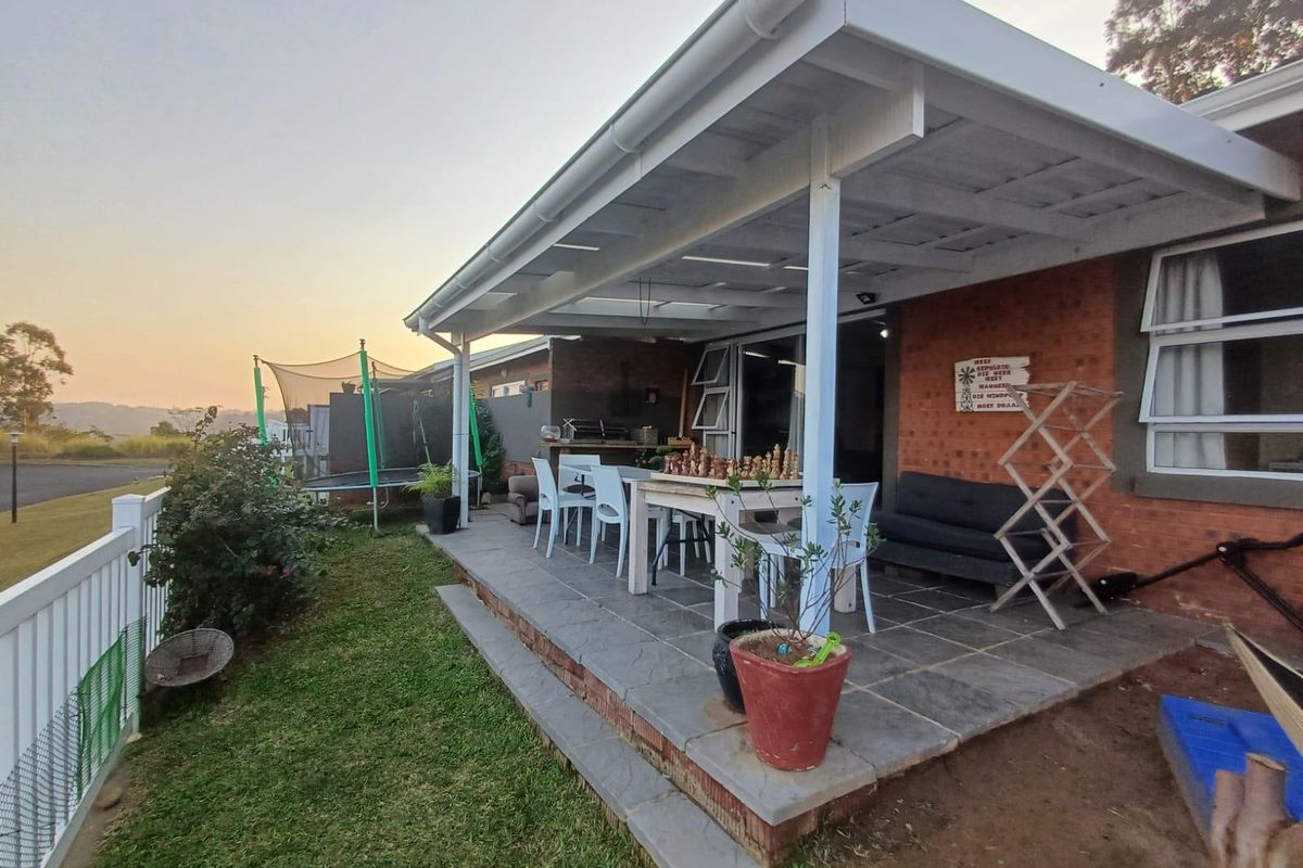 A covered outdoor patio featuring stone tile flooring and a built-in braai, providing a functional space for outdoor entertaining and relaxation.