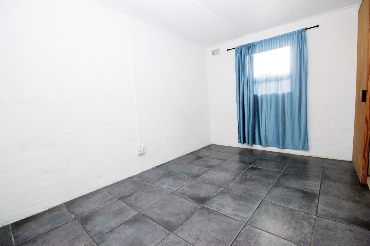 A vacant bedroom featuring dark tiled flooring and white walls, providing a blank canvas for potential interior design and furnishing.