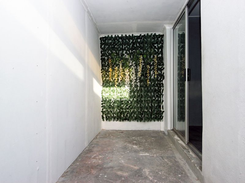 A compact, unfinished outdoor patio area featuring a sliding glass door and a decorative vertical garden wall.