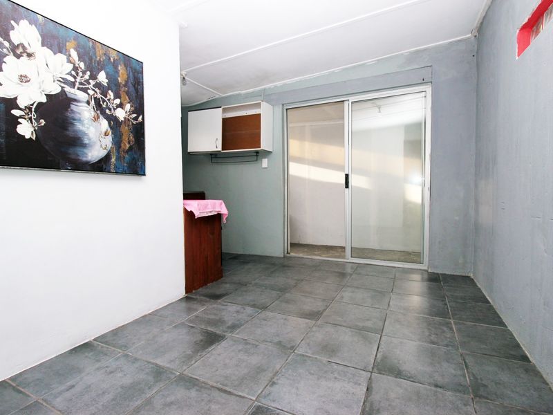 A functional utility space featuring dark tiled flooring, wall-mounted cabinetry, and a sliding glass door providing access to the exterior.