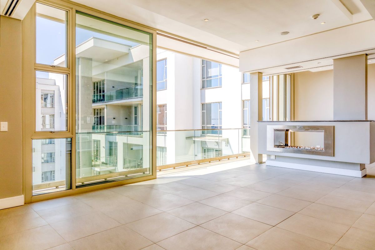 Spacious, light-filled living area featuring large sliding glass doors, modern tiled flooring, a sleek built-in fireplace, and access to a private balcony.