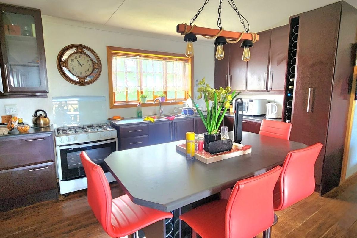 A functional kitchen featuring dark cabinetry, a gas stove, integrated wine storage, and a central island with timber flooring throughout.
